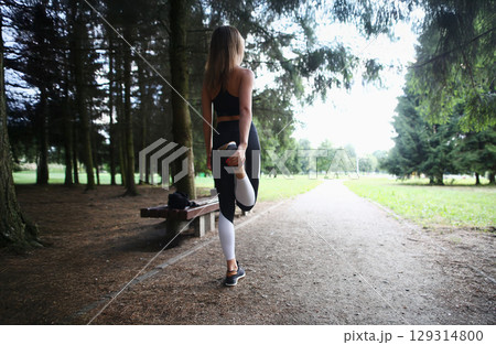 Stretching and warming up in a serene park on a fresh morning before an invigorating workout session Stretching and warming up in a serene park on a fresh morning before an invigorating workout session 129314800