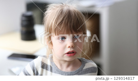 Young child with striking blue eyes engages in playful conversation in a cozy home environment during midday hours Young child with striking blue eyes engages in playful conversation in a cozy home environment during midday hours 129314817