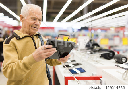 senor man pensioner buying modern tablet digital in showroom of digital electronic goods store senor man pensioner buying modern tablet digital in showroom of digital electronic goods store 129314886