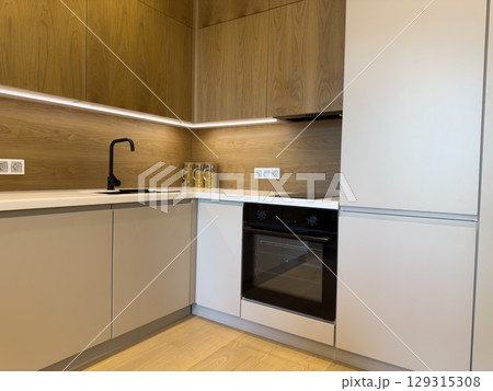 Kitchen design featuring elegant light colored cabinets, black faucet, built in oven and cooktop. Minimalistic design with functional layout and stylish finishes for contemporary living Kitchen design featuring elegant light colored cabinets, black faucet, built in oven and cooktop. Minimalistic design with functional layout and stylish finishes for contemporary living 129315308