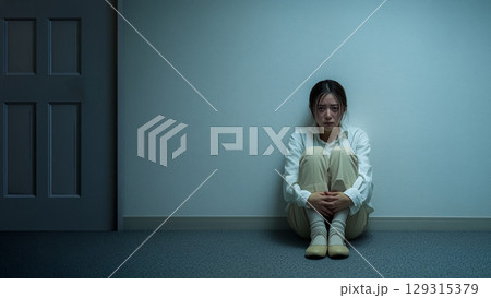 壁にもたれ不安で座る女性、感情的なポートレート 129315379