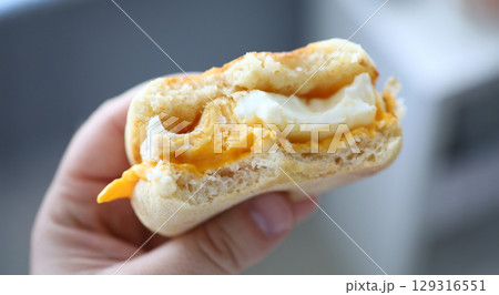 Delicious breakfast biscuit filled with creamy egg and melted cheese enjoyed in a cozy kitchen setting 129316551