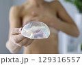 Holding an opalescent silicone breast implant in a bright, modern room during a consultation for cosmetic enhancement 129316557