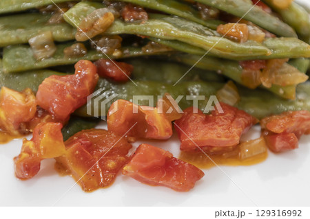 Fried green beans with tomato and onion pieces. Tasty meal with french bean on dinner or lunch on the white background Fried green beans with tomato and onion pieces. Tasty meal with french bean on dinner or lunch on the white background 129316992