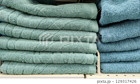 Several stacks of soft towels in shades of turquoise and teal, neatly folded and displayed on store shelf Several stacks of soft towels in shades of turquoise and teal, neatly folded and displayed on store shelf 129317426