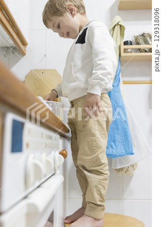 Curious child preparing food standing on stool in kitchen 129318096