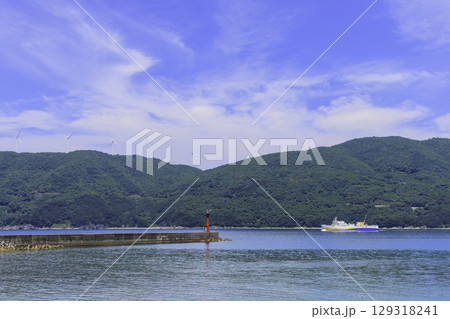 佐田岬半島の風車と赤い灯台が見える伊方町の港とフェリーの風景 129318241