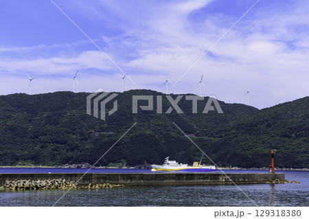 佐田岬半島の風車と赤い灯台が見える伊方町の港とフェリーの風景 129318380