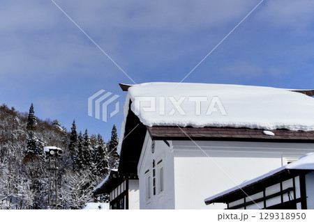 建物の屋根と山に雪が積もっている風景が綺麗 129318950