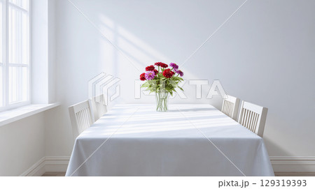 Bright and airy dining area featuring a simple white table with fresh flowers in a vase, empty wall, enhancing the minimalist decor and creating a cozy atmosphere 129319393