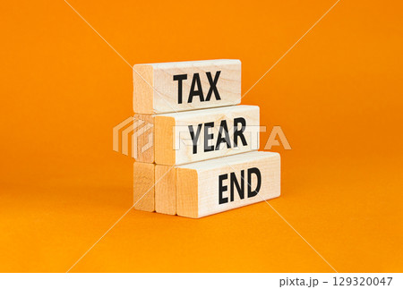 Tax year end symbol. Concept words Tax year end on beautiful wooden blocks. Beautiful orange table orange background. Business tax year end concept. Copy space. Tax year end symbol. Concept words Tax year end on beautiful wooden blocks. Beautiful orange table orange background. Business tax year end concept. Copy space. 129320047