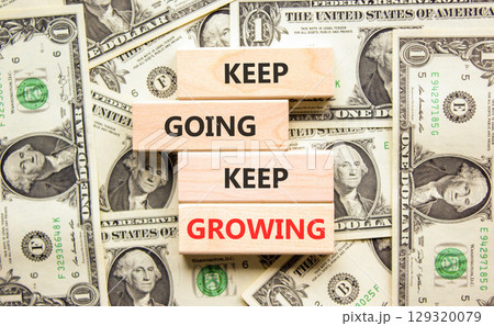 Keep going and growing symbol. Concept words phrase Keep going keep growing on beautiful wooden blocks. Dollar bills. Beautiful dollar bills background. Business Keep going growing concept. Copy space 129320079