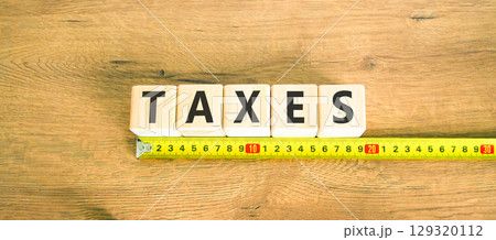Taxes symbol. Concept word Taxes on beautiful wooden blocks. Beautiful wooden table wooden background. Beautiful yellow ruler. Business lifestyle taxes concept. Copy space. 129320112