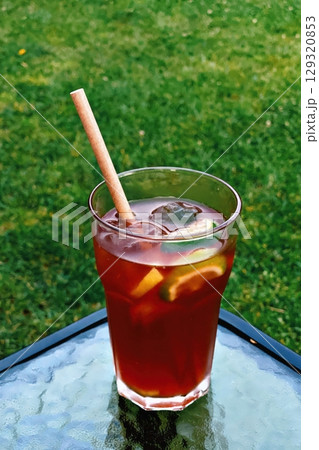 Glass of iced tea with a straw in it sits on a table. Vertical background. Wallpapers phone. 129320853