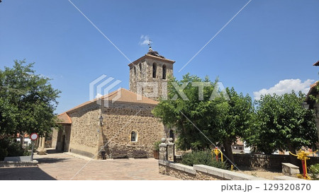 Historic stone church in scenic spanish village under a bright blue sky. Iglesia San Miguel Arcangel de Pedrezuela. Church of Saint Michael the Archangel in Pedrezuela, Spain 129320870