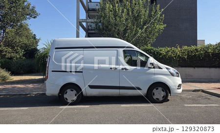 Efficient urban delivery vehicle parked on city street near modern apartment. White delivery van on the street. Copy space. Mock-up for delivery service 129320873