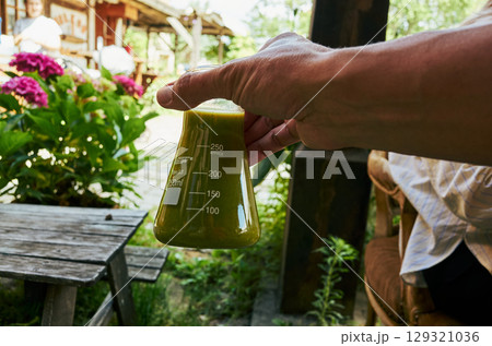 Person is holding a green liquid in a beaker 129321036
