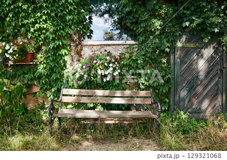 Wooden bench is sitting in front of a house with a green door 129321068