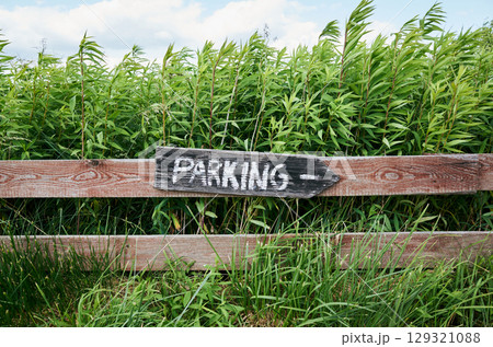 Sign that says parking is on a wooden fence Sign that says parking is on a wooden fence 129321088