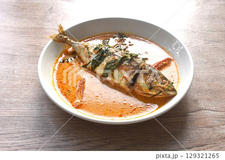 spicy boiled mackerel topping chop lemon grass in red curry sauce on plate  129321265