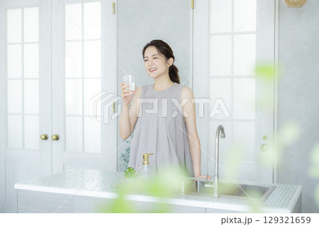 キッチンで水を飲むミドルの女性 キッチンで水を飲むミドルの女性 129321659