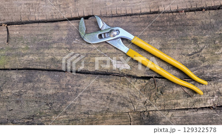 Plumber's adjustable wrench on wooden surface for home repair and maintenance. Pipe wrench, Swedish wrench. Horizontal banner. Copy space 129322578