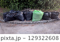 Environmental waste management: collection of black and green garbage bags on street for recycling and disposal 129322608