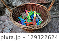 Colorful clothespins in wicker basket against stone background. Clothes pegs 129322624
