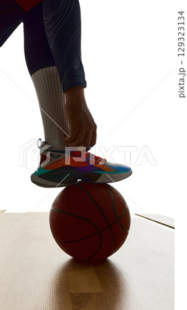 Close-up of basketball shoe on ball with dramatic backlight and focus on precision 129323134