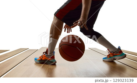 Basketball player in mid-dribble motion on wooden court with dynamic posture Basketball player in mid-dribble motion on wooden court with dynamic posture 129323139