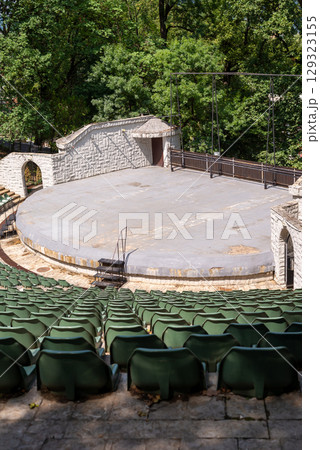 Amphitheater with concentric rows of tiered seating curving around a central stage area under an open sky 129323155
