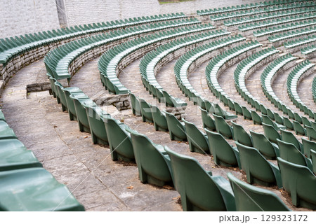 Large, open-air stone amphitheater is filled with numerous rows of green plastic seats arranged in a semi-circular pattern Large, open-air stone amphitheater is filled with numerous rows of green plastic seats arranged in a semi-circular pattern 129323172