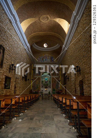 Interior of a Historic Stone Church Featuring Wooden Benches, Religious Artwork, and Natural Light Interior of a Historic Stone Church Featuring Wooden Benches, Religious Artwork, and Natural Light 129326361