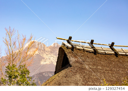 積雪の由布岳と茅葺き屋根 129327454