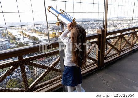 A little girl looks through a large telescope on an observation deck A little girl looks through a large telescope on an observation deck 129328054