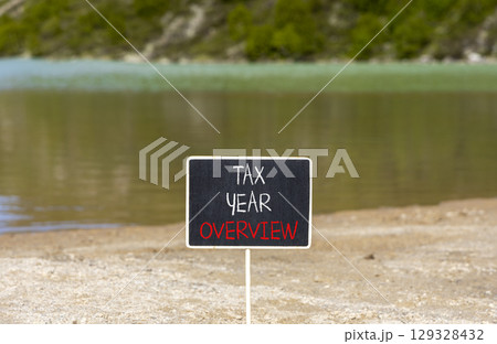 Tax year overview symbol. Concept words Tax year overview on beautiful black yellow blackboard. Beautiful mountain lake background. Business tax year overview concept. Copy space. Tax year overview symbol. Concept words Tax year overview on beautiful black yellow blackboard. Beautiful mountain lake background. Business tax year overview concept. Copy space. 129328432