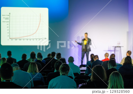Speaker presents data analysis graph at technology conference in auditorium 129328560