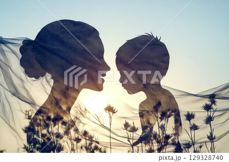 Silhouettes of a woman and child facing each other with a sheer fabric and wildflowers in the foreground. Concept of family connection and love. For family-themed art. 129328740