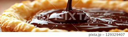 Chocolate sauce is being poured into a flaky crust. Concept of dessert preparation and indulgence. For food photography. 129329407