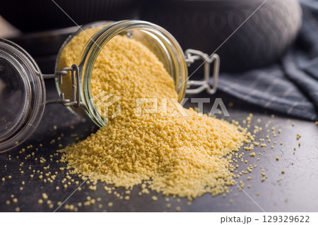 Raw couscous in jar on black table. Raw couscous in jar on black table. 129329622