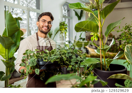 Handsome young man with plenty green plants in the flower shop Handsome young man with plenty green plants in the flower shop 129329629