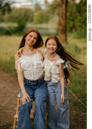 Happy Sisters Smiling Outdoors on a Sunny Day 129329896