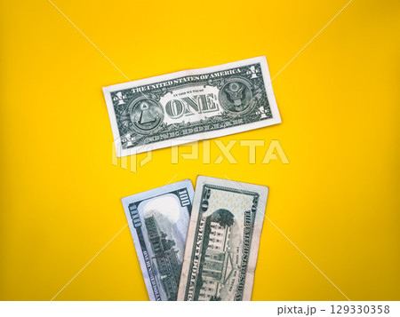 One dollar and a couple of dollar bills, on a yellow background, in the center of the image, top view One dollar and a couple of dollar bills, on a yellow background, in the center of the image, top view 129330358