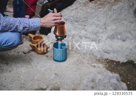 Person Preparing Outdoor Coffee on Portable Stove During Camping Adventure Person Preparing Outdoor Coffee on Portable Stove During Camping Adventure 129330535