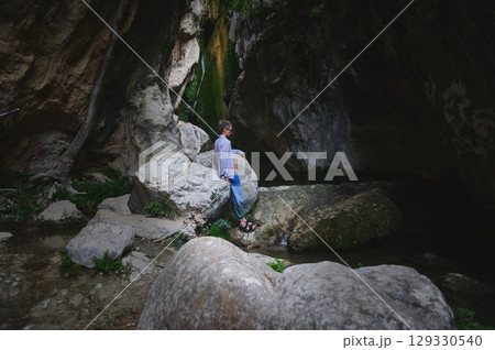 Man Standing Amid Rocky Gorge and Greenery with Water Stream Man Standing Amid Rocky Gorge and Greenery with Water Stream 129330540