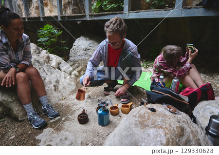 Group of Campers Preparing Coffee Outdoors in a Natural Setting 129330628
