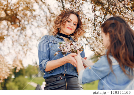 Fashionable mother with daughter. Family in a spring park. Woman in a blue shirt Fashionable mother with daughter. Family in a spring park. Woman in a blue shirt 129331169