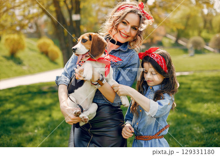 Beautiful mother with daughter. Family in a spring park. Woman in a blue shirt. Family with a cute dog Beautiful mother with daughter. Family in a spring park. Woman in a blue shirt. Family with a cute dog 129331180