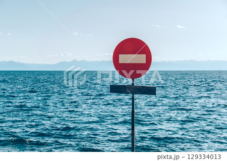 The movement of vehicles is prohibited. Road sign on the background of the sky and the ocean. Stop. 129334013