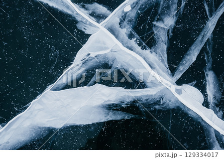 intricate patterns and textures ice cracks on frozen lake captured during winter peak. closeup. 129334017